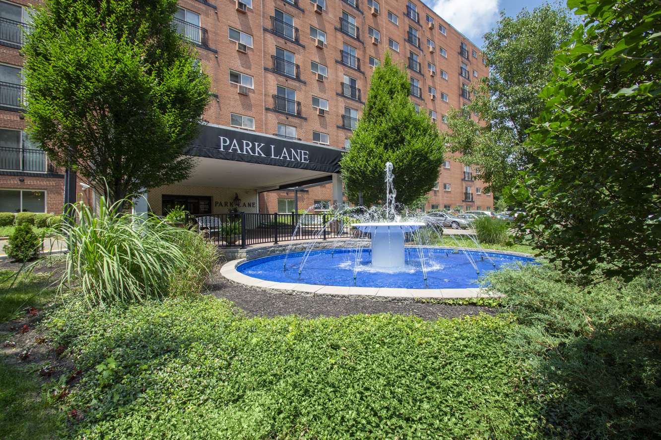 This is a photo of the building exterior featuring the fountain in front of the entrance to Park Lane Apartments in Cincinnati, OH.