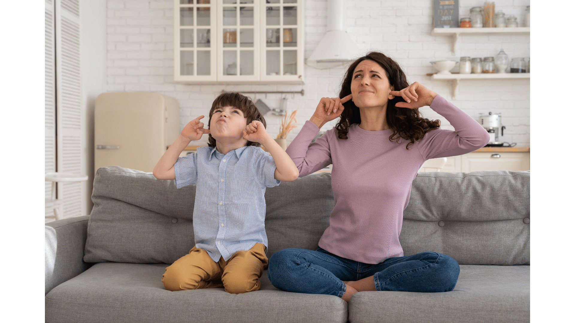 Frowning Mom and Son Sit on Couch with Closed Eyes and Plugged Ears from Upstairs Noise